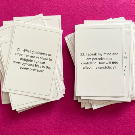 Two stacks of white cards on a hot pink surface. There is a question printed on the top card of each stack.